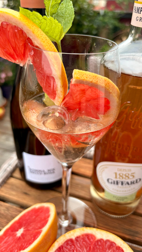 Grapefruit Aperitif im Sektflas mit Eiwürfeln und Grapefruit Scheibe. 